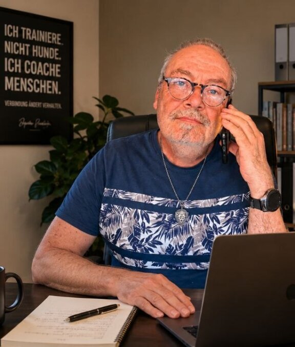 Man sieht auf dem Foto wie Thorsten Funk am Schreibtisch sitzt und mit einem Kunden telefoniert